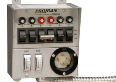 Transfer switch with six toggle switches, labeled A to F, colored sockets, and a round connector, mounted on a wall.