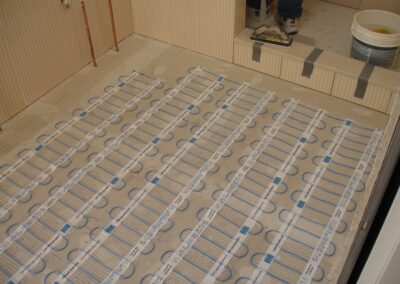 Electric underfloor heating system being installed, with heating mats laid out on a tiled bathroom floor.