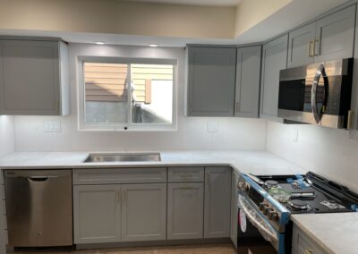 Modern kitchen with gray cabinets, stainless steel appliances, including an oven, microwave, and dishwasher, and a window above the sink.