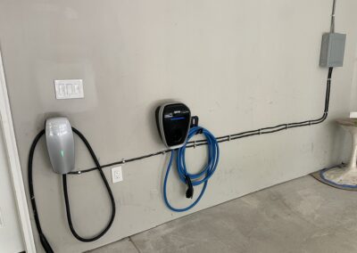 Wall-mounted EV chargers with connected cables in a garage setting.